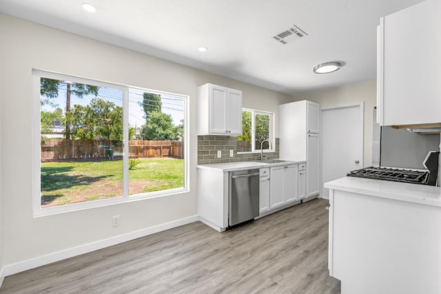 4729 E Cornell Ave, Fresno, CA 93703 - kitchen with stainless steel dishwasher, light countertops, white cabinetry, light wood-style floors, and tasteful backsplash