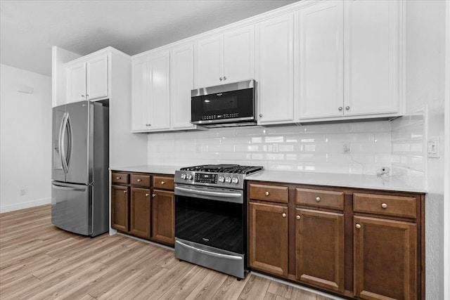 2062 N Osmun Ave, Clovis, CA 93619 - kitchen with appliances with stainless steel finishes, light wood finished floors, light countertops, tasteful backsplash, and white cabinetry