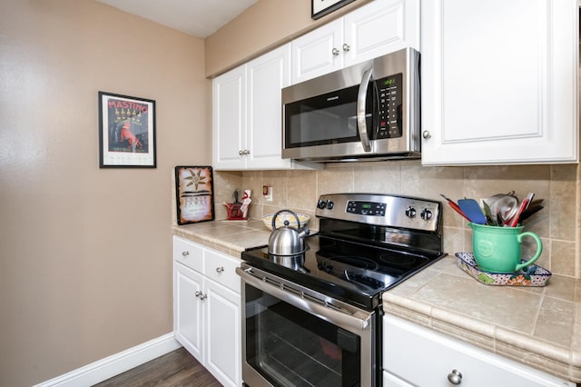 5090 N College Ave Unit 103, Fresno, CA 93704 - kitchen featuring appliances with stainless steel finishes, white cabinets, backsplash, and tile counters