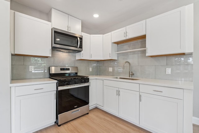 4545 E Grant Ave, Fresno, CA 93702 - kitchen with appliances with stainless steel finishes, white cabinetry, light countertops, light wood-type flooring, and backsplash