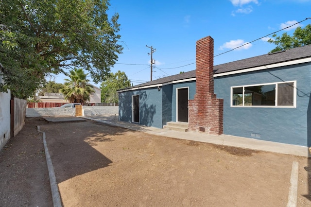 4545 E Grant Ave, Fresno, CA 93702 - back of house featuring stucco siding, entry steps, and a chimney