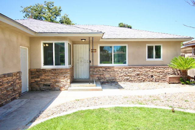 3377 E Richert Ave, Fresno, CA 93726 - view of exterior entry with stone siding, a shingled roof, and stucco siding