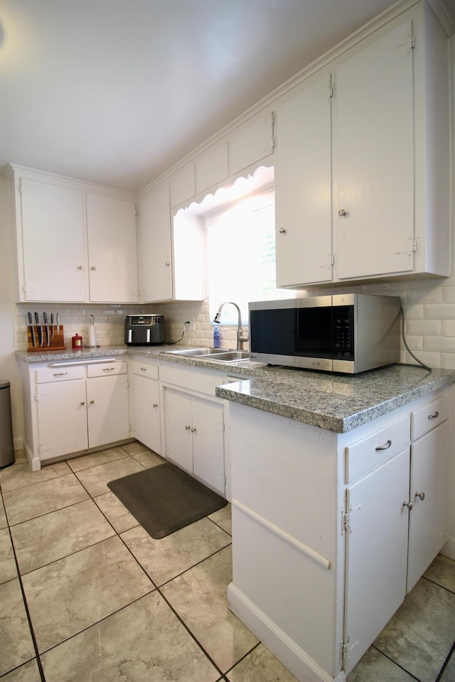 3377 E Richert Ave, Fresno, CA 93726 - kitchen with stainless steel microwave, decorative backsplash, white cabinetry, and light countertops