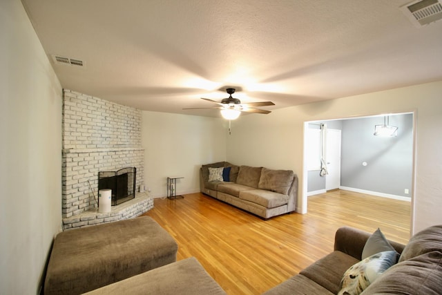 3377 E Richert Ave, Fresno, CA 93726 - living area featuring a ceiling fan, light wood-type flooring, a fireplace, and a textured ceiling