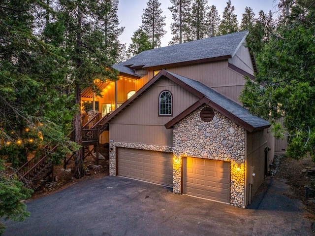 40416 Wild Rose Ln, Shaver Lake, CA 93664 - view of front facade with stone siding, asphalt driveway, stairs, a shingled roof, and an attached garage