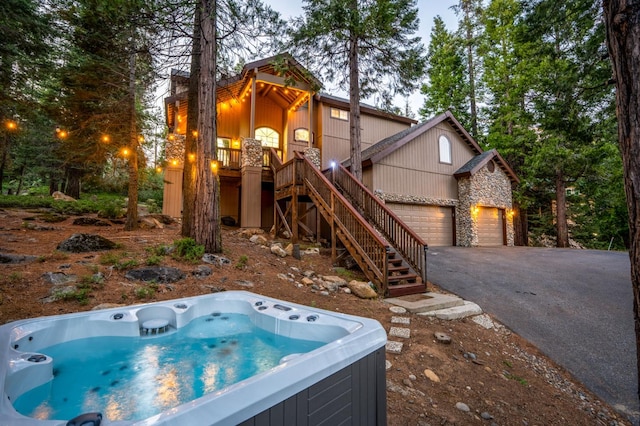 40416 Wild Rose Ln, Shaver Lake, CA 93664 - view of front facade featuring a hot tub, stone siding, stairway, an attached garage, and asphalt driveway