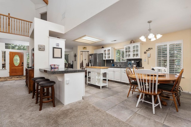 40416 Wild Rose Ln, Shaver Lake, CA 93664 - kitchen with a peninsula, white cabinetry, a chandelier, freestanding refrigerator, and a breakfast bar