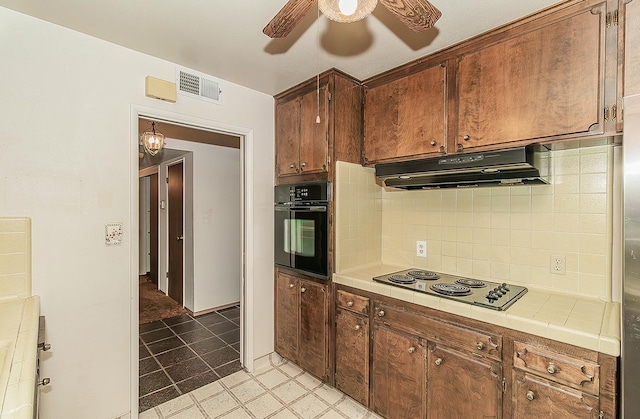 4368 N Hughes Ave, Fresno, CA 93705 - kitchen featuring black oven, under cabinet range hood, tile countertops, electric cooktop, and a ceiling fan