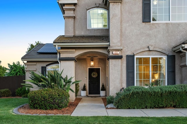 632 W Palo Alto Ave, Clovis, CA 93612 - exterior entry at dusk featuring roof mounted solar panels, stucco siding, and a tile roof