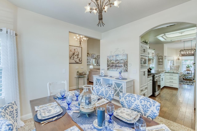 212 W Everglade Ave, Clovis, CA 93619 - dining area with arched walkways, a chandelier, and dark wood-type flooring