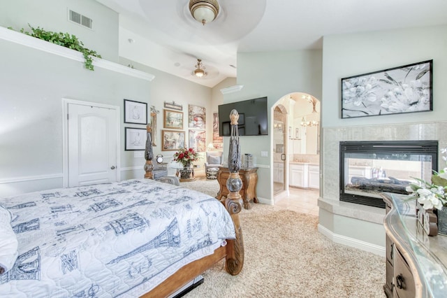 212 W Everglade Ave, Clovis, CA 93619 - carpeted bedroom featuring lofted ceiling, arched walkways, a multi sided fireplace, connected bathroom, and tile patterned flooring