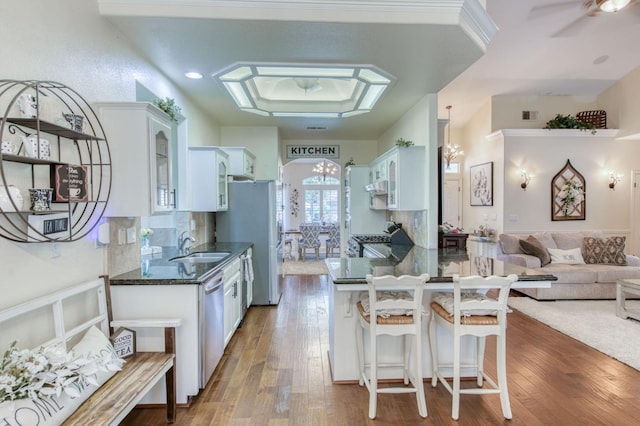 212 W Everglade Ave, Clovis, CA 93619 - kitchen featuring stainless steel appliances, glass insert cabinets, white cabinetry, wood finished floors, and a kitchen bar