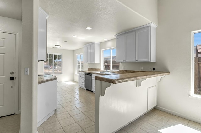 840 Morris Ln, Madera, CA 93637 - kitchen with stainless steel dishwasher, a kitchen bar, light tile patterned floors, recessed lighting, and a textured ceiling
