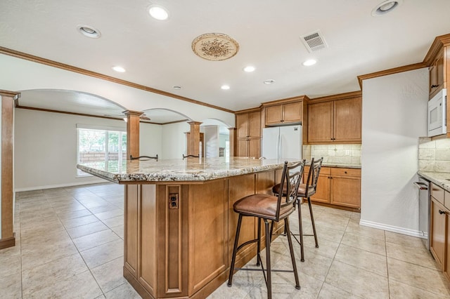 3348 W Sierra Ave, Fresno, CA 93711 - kitchen with white appliances, ornate columns, a breakfast bar, tasteful backsplash, and ornamental molding