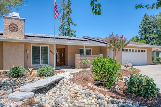 3348 W Sierra Ave, Fresno, CA 93711 - ranch-style house with stucco siding, an attached garage, roof mounted solar panels, driveway, and covered porch