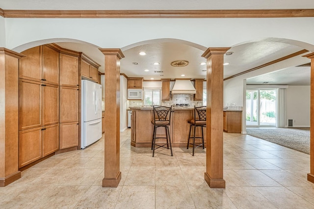 3348 W Sierra Ave, Fresno, CA 93711 - kitchen featuring white appliances, crown molding, premium range hood, brown cabinets, and decorative backsplash