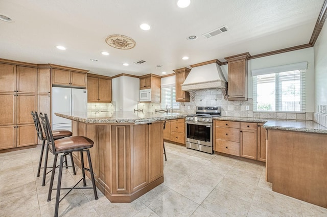 3348 W Sierra Ave, Fresno, CA 93711 - kitchen with white appliances, custom exhaust hood, a breakfast bar, backsplash, and crown molding