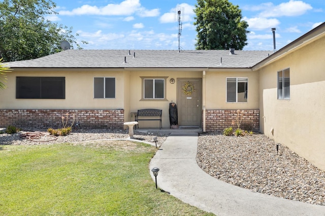 1446 Pico Ave, Clovis, CA 93611 - view of exterior entry with brick siding, a lawn, stucco siding, and a shingled roof