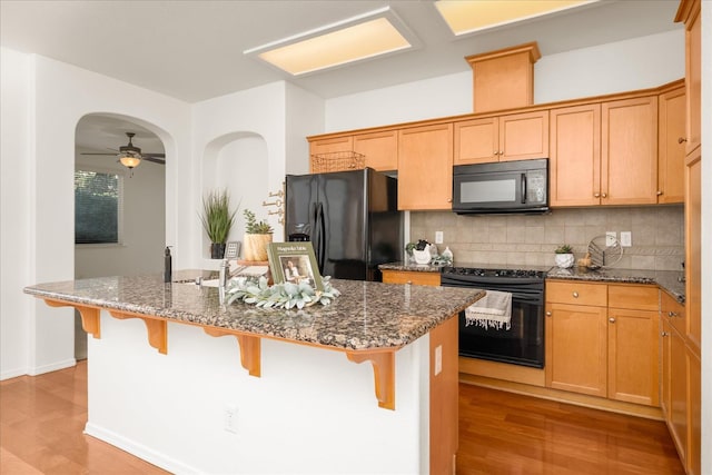 1935 N Glen Alva Ln, Clovis, CA 93619 - kitchen featuring black appliances, light wood-style flooring, backsplash, dark stone countertops, and a ceiling fan