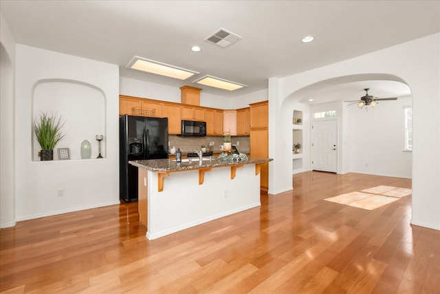 1935 N Glen Alva Ln, Clovis, CA 93619 - kitchen with black appliances, arched walkways, a center island with sink, a kitchen breakfast bar, and ceiling fan