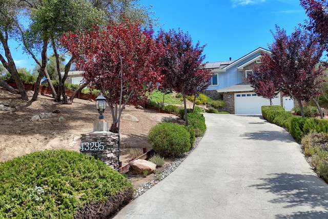 43295 Running Deer Dr, Coarsegold, CA 93614 - view of property hidden behind natural elements with roof mounted solar panels, concrete driveway, and a garage