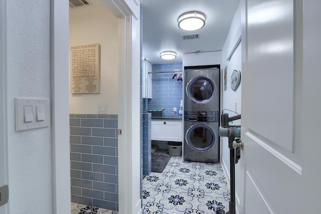 43295 Running Deer Dr, Coarsegold, CA 93614 - laundry room with stacked washing machine and dryer, tile walls, and light tile patterned floors