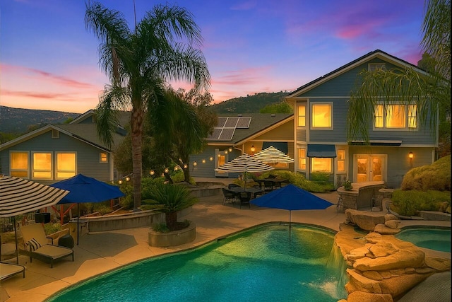 43295 Running Deer Dr, Coarsegold, CA 93614 - back of property at dusk featuring french doors, a patio area, an outdoor pool, outdoor dining area, and solar panels