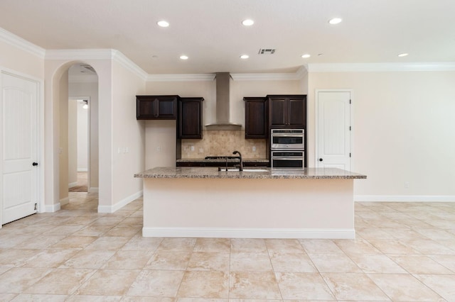 7399 N Riverside Dr, Fresno, CA 93722 - kitchen with wall chimney exhaust hood, light stone countertops, appliances with stainless steel finishes, a kitchen island with sink, and recessed lighting