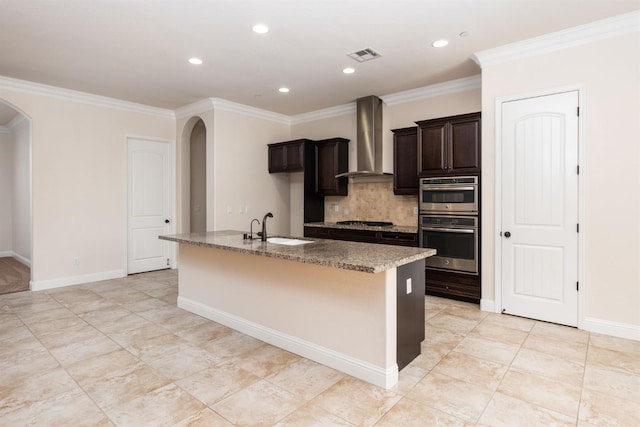 7399 N Riverside Dr, Fresno, CA 93722 - kitchen with wall chimney exhaust hood, arched walkways, appliances with stainless steel finishes, an island with sink, and decorative backsplash