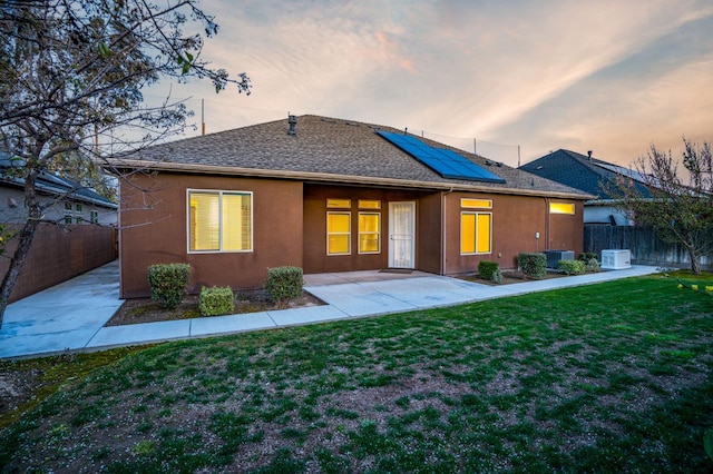 7399 N Riverside Dr, Fresno, CA 93722 - back of property featuring solar panels, a patio area, a fenced backyard, roof with shingles, and stucco siding