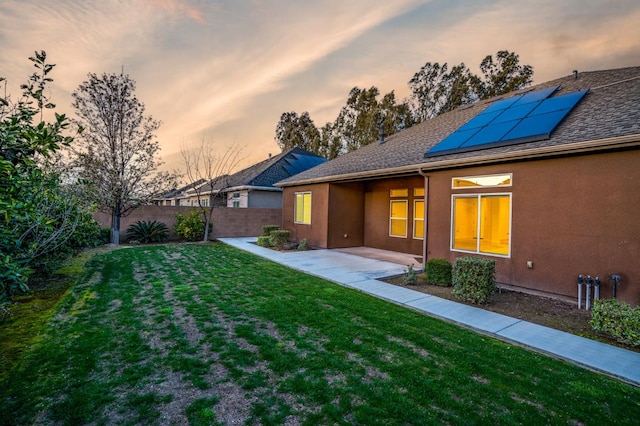 7399 N Riverside Dr, Fresno, CA 93722 - back of property at dusk featuring solar panels, stucco siding, a patio, and roof with shingles