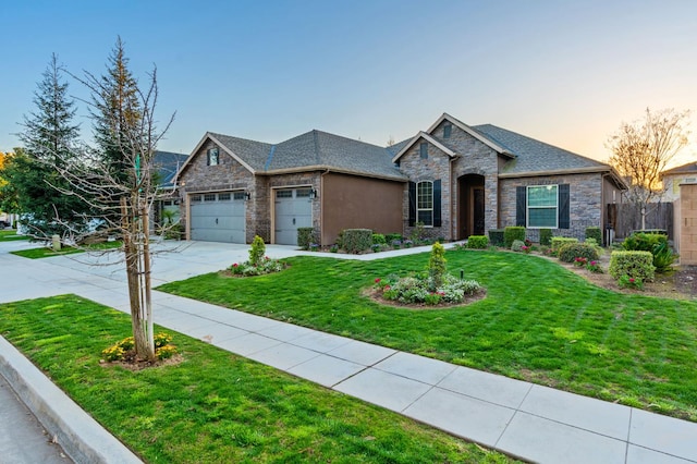 7399 N Riverside Dr, Fresno, CA 93722 - view of front of house featuring stone siding, a garage, a yard, and driveway