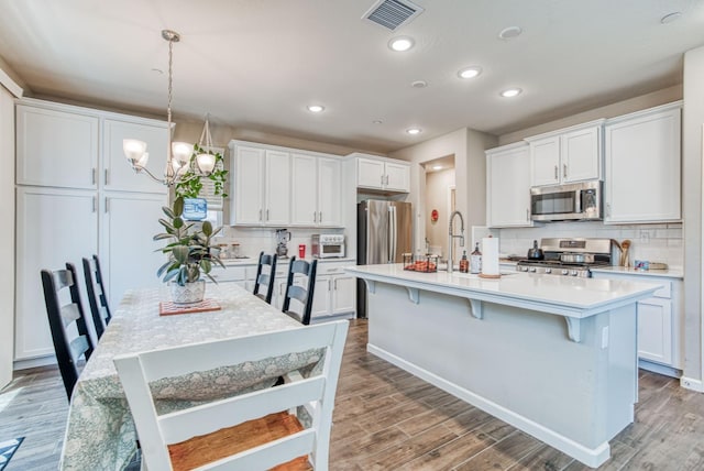 212 Arbor Dr S, Madera, CA 93636 - kitchen with stainless steel appliances, tasteful backsplash, a chandelier, a kitchen bar, and light countertops