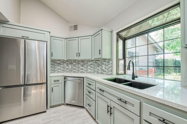 7047 N Teilman Ave Unit 102, Fresno, CA 93711 - kitchen with stainless steel appliances, vaulted ceiling, backsplash, light stone counters, and light wood-style flooring