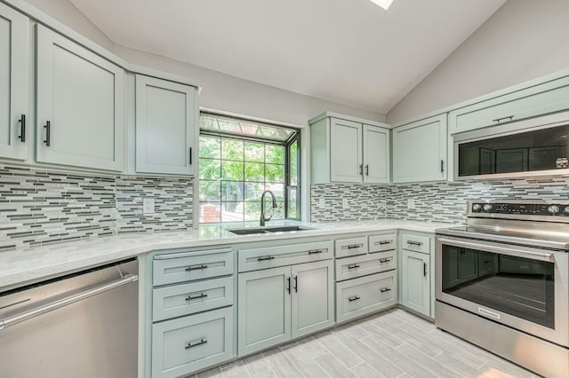 7047 N Teilman Ave Unit 102, Fresno, CA 93711 - kitchen with stainless steel appliances, vaulted ceiling, backsplash, and light wood-style floors