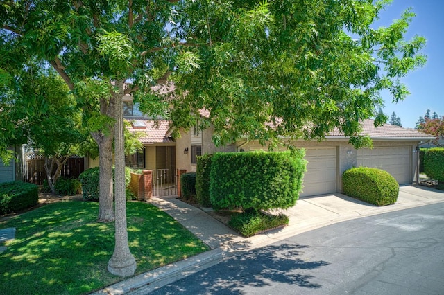 7047 N Teilman Ave Unit 102, Fresno, CA 93711 - obstructed view of property featuring driveway, a tile roof, stucco siding, and an attached garage