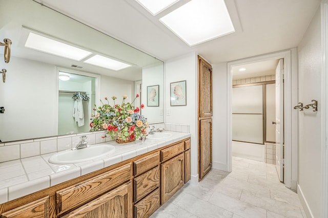 7047 N Teilman Ave Unit 102, Fresno, CA 93711 - bathroom featuring double vanity, a shower with door, and marble look tiles