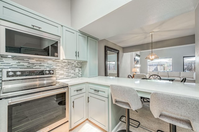 7047 N Teilman Ave Unit 102, Fresno, CA 93711 - kitchen with stainless steel appliances, backsplash, light countertops, decorative light fixtures, and a kitchen bar