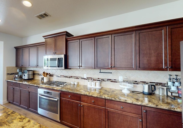 4367 Salem Ln, Clovis, CA 93619 - kitchen featuring appliances with stainless steel finishes, backsplash, light stone counters, and recessed lighting