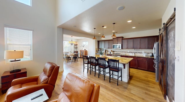 4367 Salem Ln, Clovis, CA 93619 - kitchen with stainless steel appliances, light wood-type flooring, a breakfast bar, open floor plan, and light stone countertops