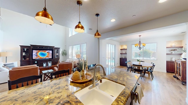 4367 Salem Ln, Clovis, CA 93619 - kitchen with light wood-style floors, pendant lighting, open floor plan, a chandelier, and a textured ceiling