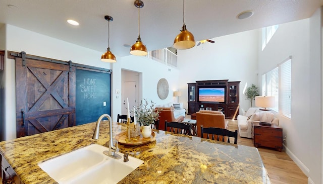 4367 Salem Ln, Clovis, CA 93619 - kitchen with light wood-style floors, decorative light fixtures, a barn door, a ceiling fan, and light stone countertops