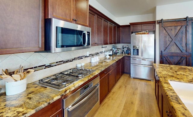 4367 Salem Ln, Clovis, CA 93619 - kitchen with stainless steel appliances, light wood finished floors, light stone countertops, tasteful backsplash, and a barn door
