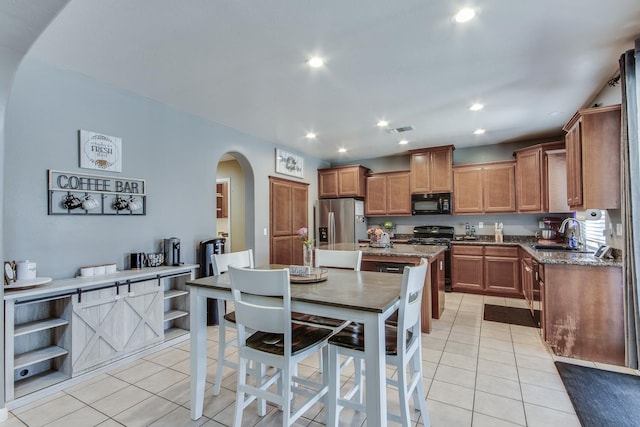 7230 E Dayton Ave, Fresno, CA 93737 - kitchen featuring black microwave, stainless steel refrigerator with ice dispenser, arched walkways, light tile patterned flooring, and recessed lighting