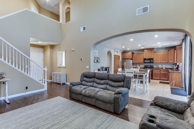 7230 E Dayton Ave, Fresno, CA 93737 - living area featuring arched walkways, light wood-type flooring, a high ceiling, recessed lighting, and stairs