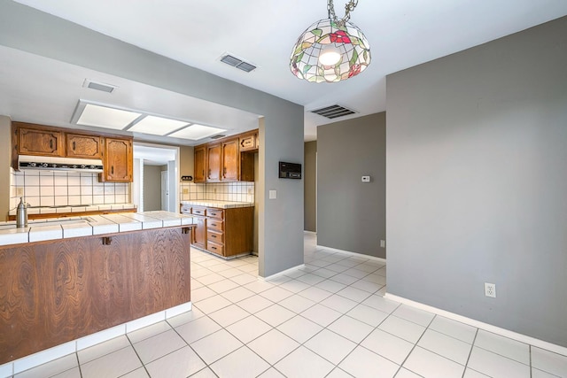 2076 W Calimyrna Ave Unit 102, Fresno, CA 93711 - kitchen featuring brown cabinets, exhaust hood, decorative backsplash, and tile counters