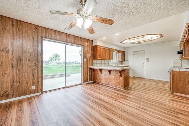 11016 E S Ave, Selma, CA 93662 - kitchen with tile countertops, brown cabinetry, a peninsula, backsplash, and a textured ceiling