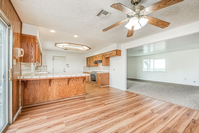 11016 E S Ave, Selma, CA 93662 - kitchen featuring open floor plan, a peninsula, stainless steel electric stove, tile countertops, and brown cabinetry