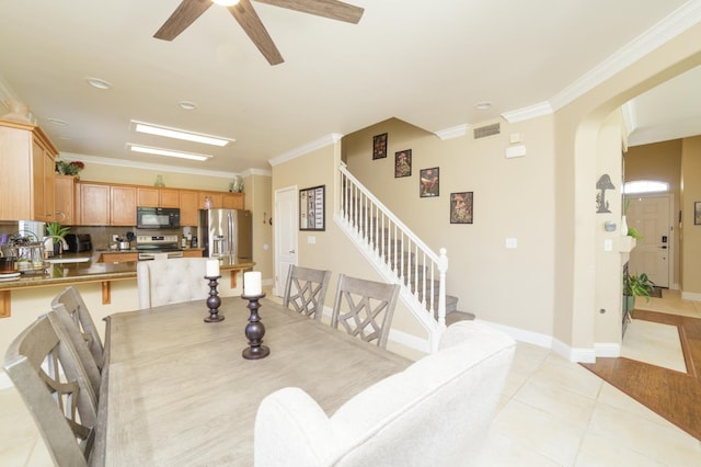 4001 W Fig Tree Ln, Fresno, CA 93722 - dining area with arched walkways, crown molding, ceiling fan, stairway, and light tile patterned floors