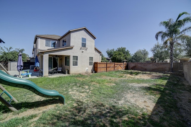 4001 W Fig Tree Ln, Fresno, CA 93722 - rear view of house with a fenced backyard, a ceiling fan, stucco siding, and a playground